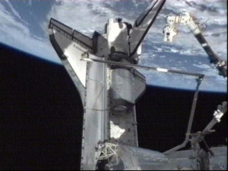 The Discovery is seen docked with the International Space Station with the ammonia tank assembly and the cargo carrier module stowed in it's payload bay.